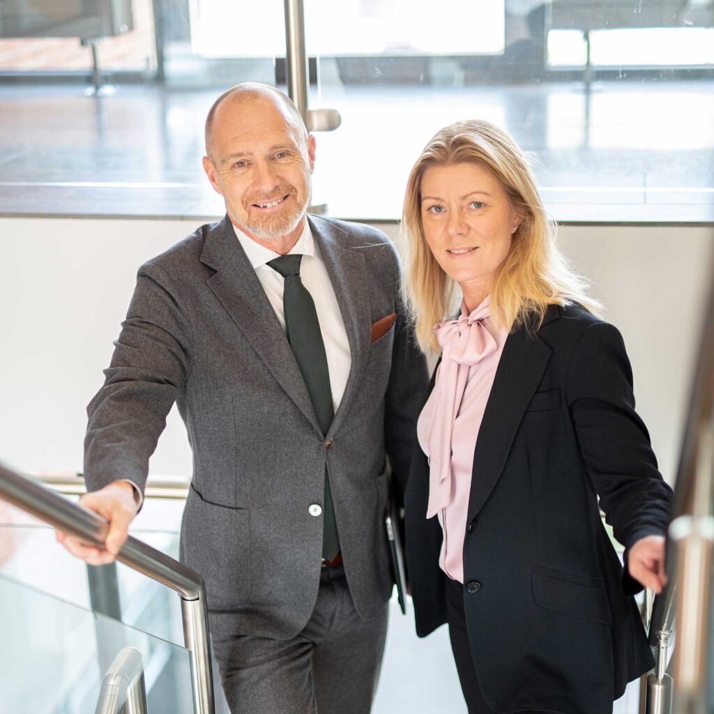 Maria Hägnander och Johan Svedberg står i en trappa och tittar in in kameran